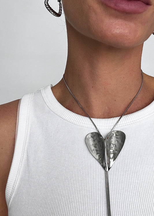 Collier cravate argenté en acier inoxydable avec pendentif cœur, au design fin, élégant et moderne.