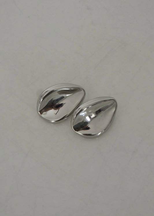 Boucles d’oreilles argentées en acier inoxydable au design organique, forme sculpturale et moderne, finition brillante.