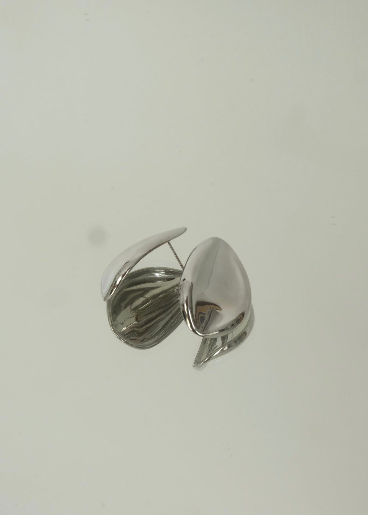 Boucles d’oreilles argentées en acier inoxydable au design organique, forme sculpturale et moderne, finition brillante.