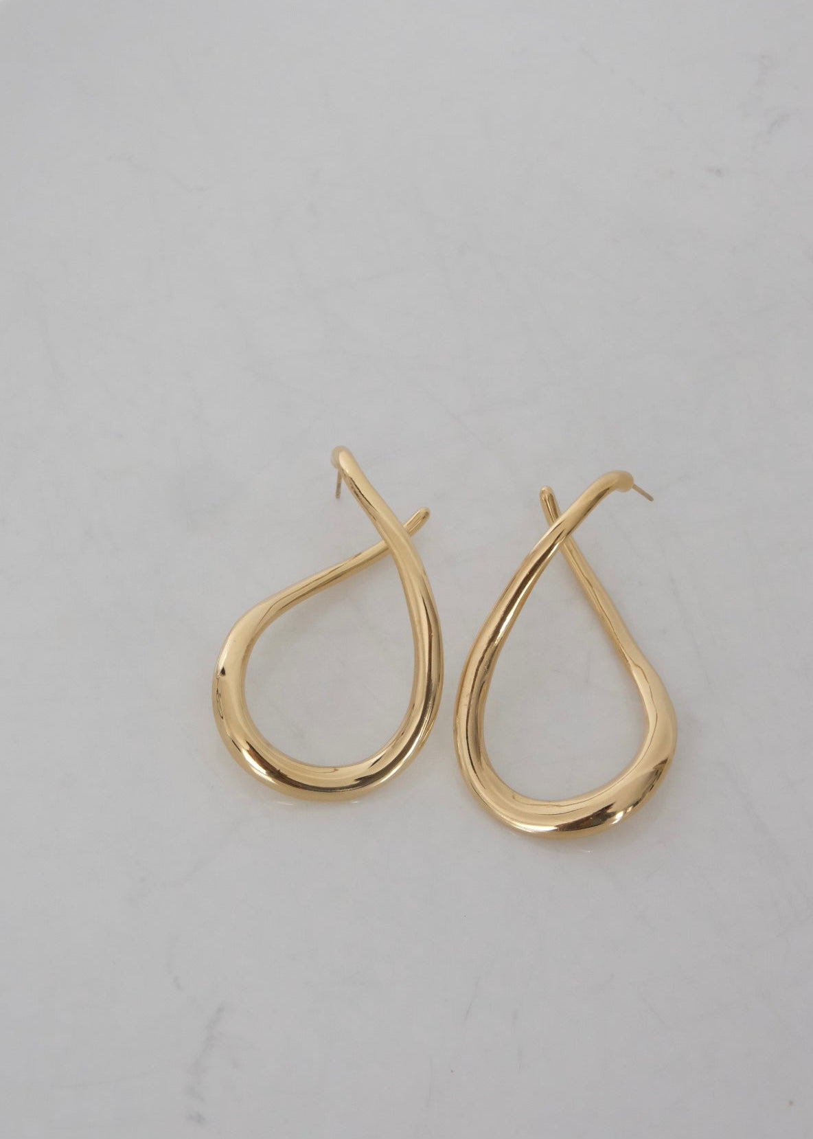 Boucles d’oreilles dorées en acier inoxydable en forme abstraite, avec fermoir puce, au design moderne et lumineux.