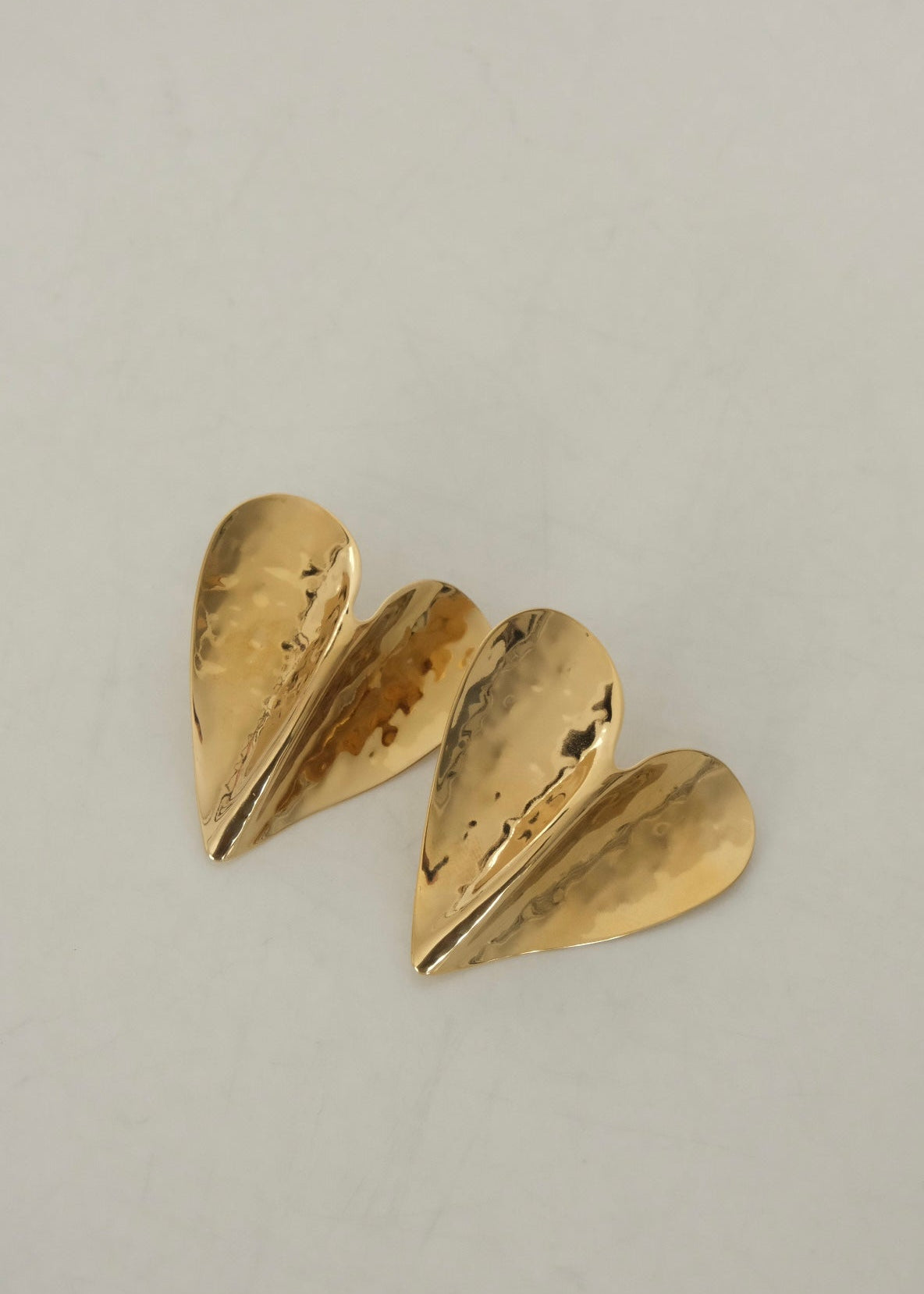 Boucles d’oreilles dorées en acier inoxydable en forme de cœur, finition effet martelé, avec fermoir puce.