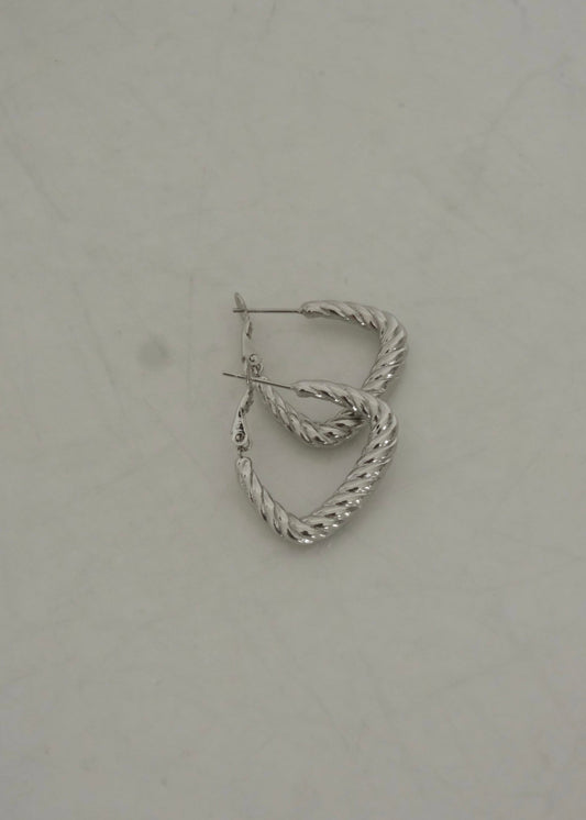 Créoles argentées en acier inoxydable, en forme de triangle torsadé, style moderne et géométrique.