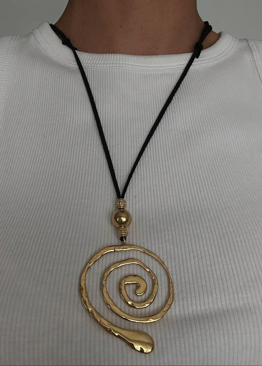 Sautoir en acier inoxydable doré avec pendentif en spirale et cordon noir ajustable, au design moderne et minimaliste.
